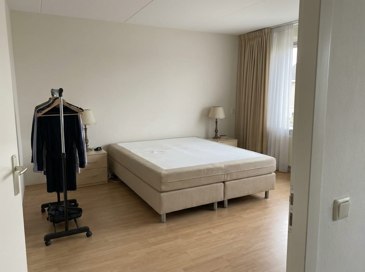 Gedateerde slaapkamer met kale matras en beige gordijnen